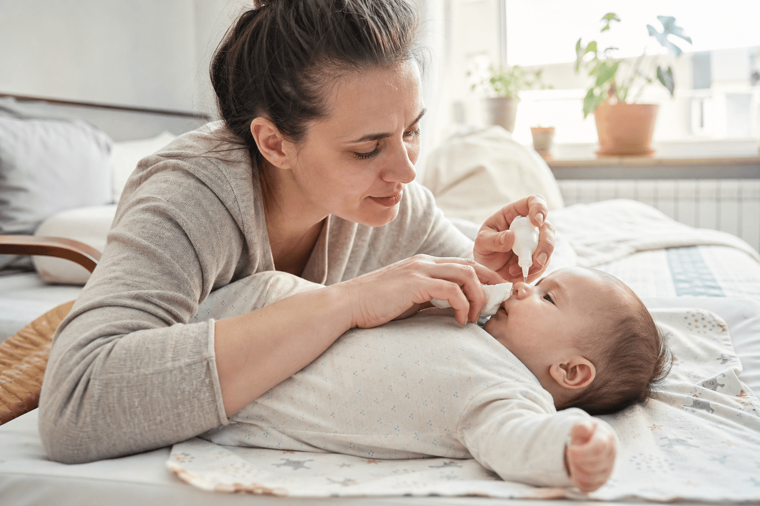 Parinte care curata bland nasul unui bebelus intr-o scena realista de acasa