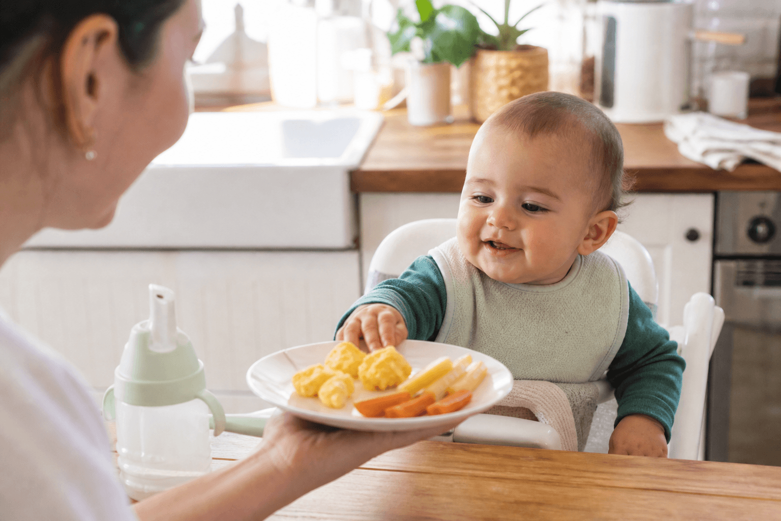 Baby in a high chair reaching for well-cooked egg and soft finger foods, bright kitchen, realistic editorial lifestyle photo