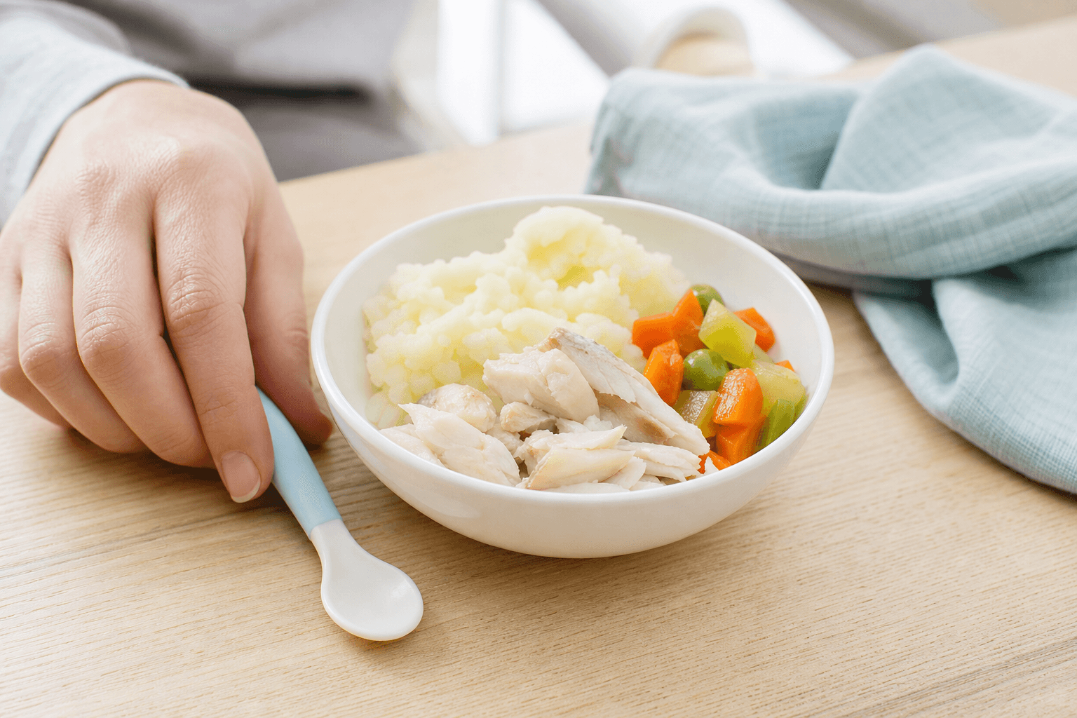 A small bowl with well-cooked fish and vegetables on a kitchen table, natural light, editorial food photo