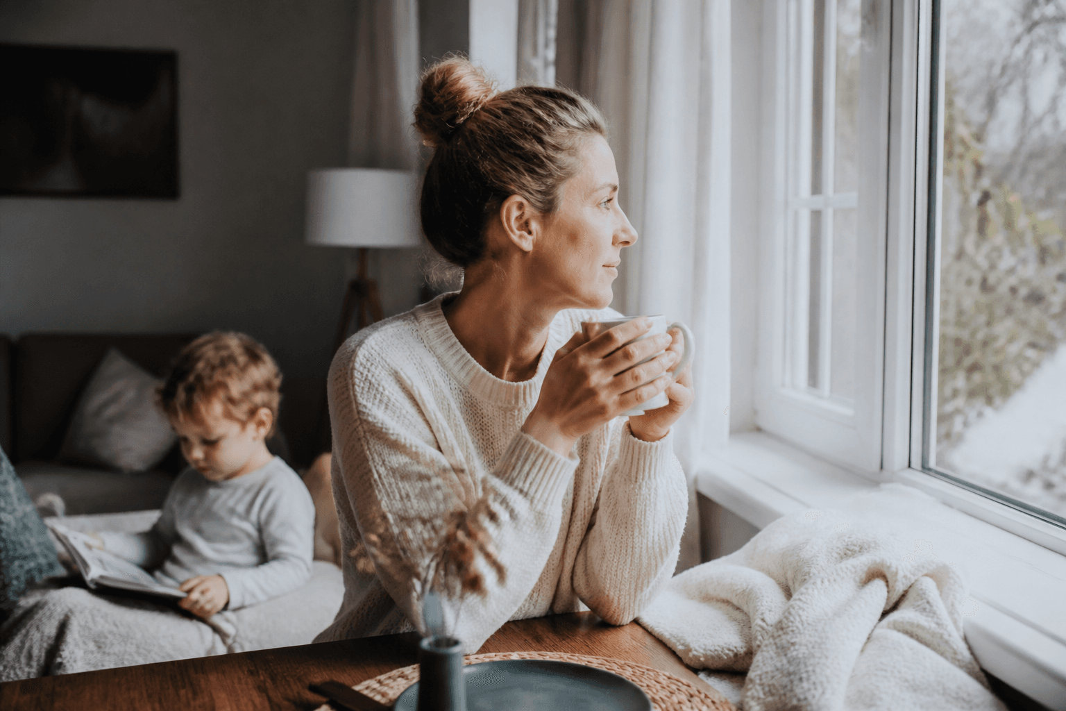 Parinte ingrijind un copil racit pe canapea, cu servetele si ceai langa el, intr-o scena calma de familie, fara text sau logo